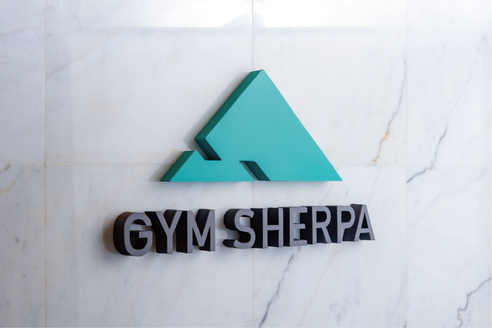 大理石の壁面に設置されたGYM SHERPAの立体ロゴサイン