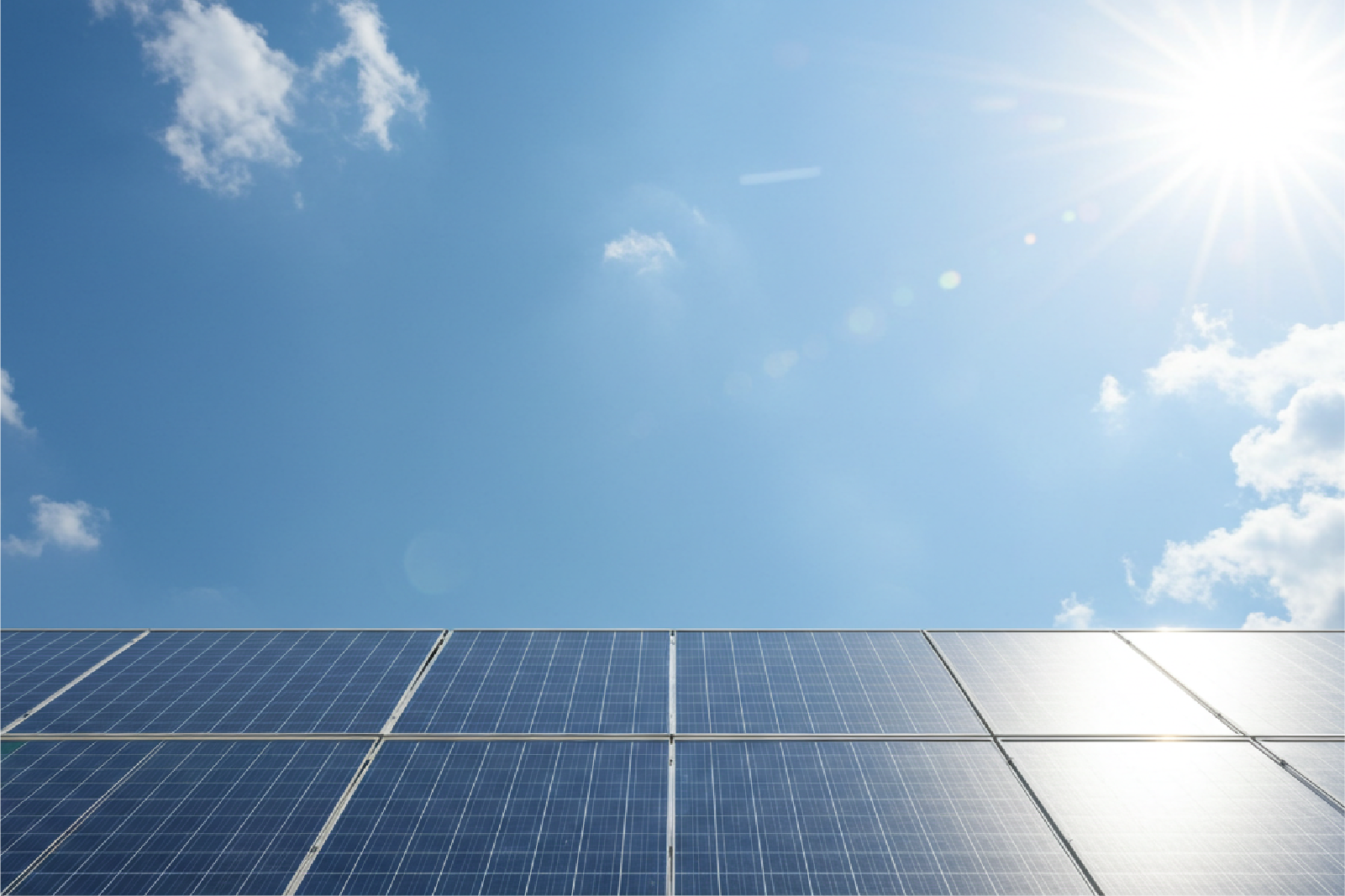 晴天の下に並ぶ太陽光発電用のソーラーパネルと強い日差し