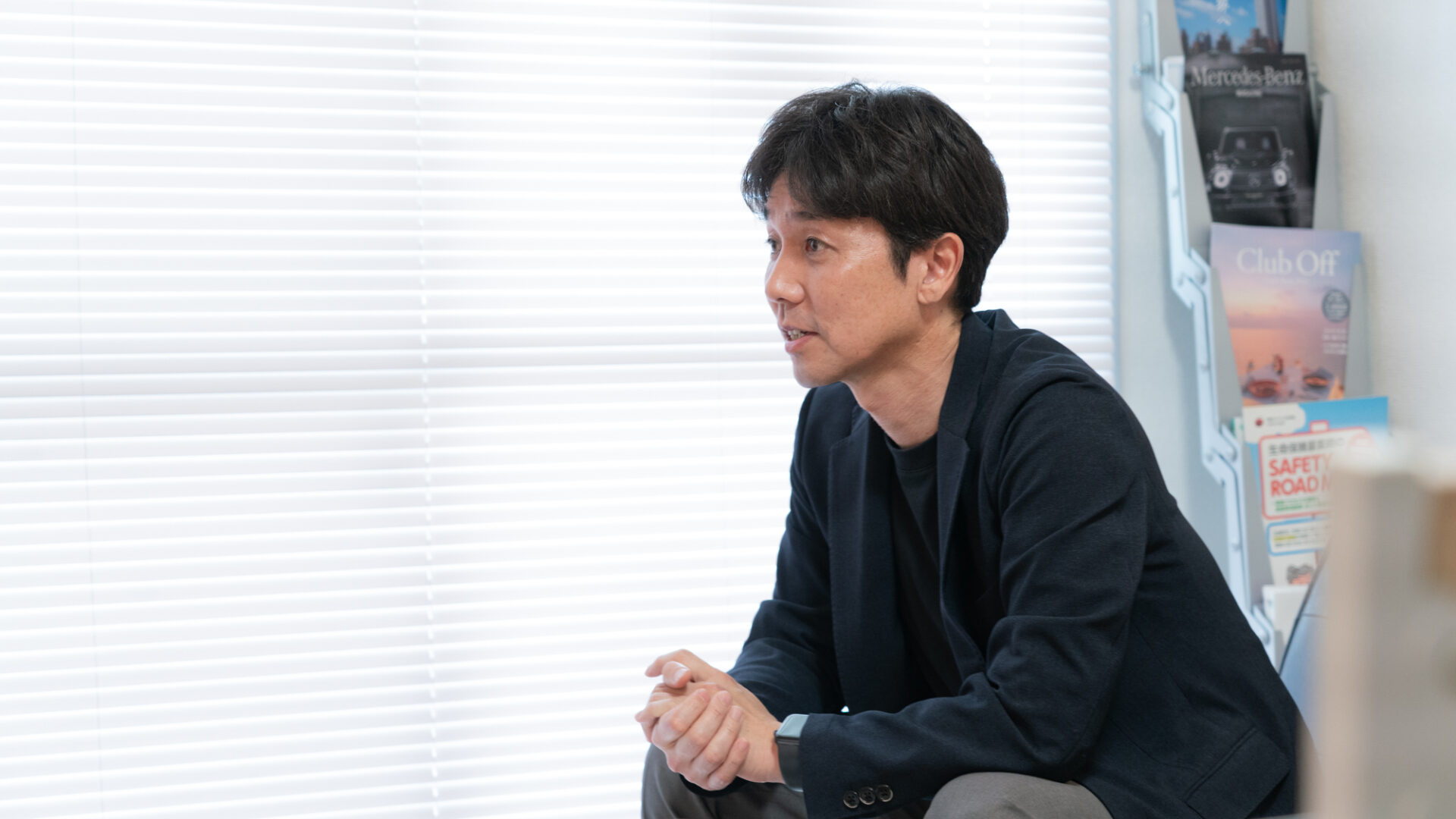 ビジネスカジュアルの代表衞藤が椅子に座り、真剣な表情で話を聞いている相談シーン