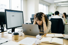 パソコンの前で頭を抱え、ホームページ更新のネタが思いつかず悩んでいるWeb担当者